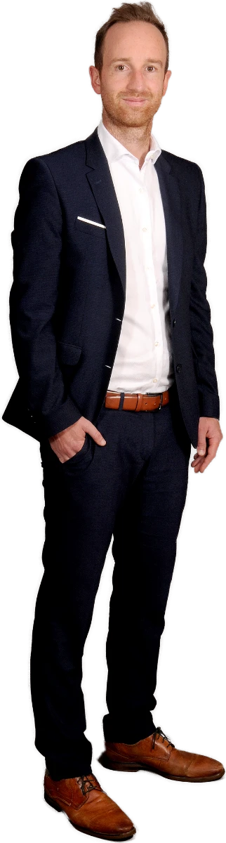 Ein schlanker Mann mit hellem Teint, hellbraunem Haar und freundlichem Lächeln, im dunklen Anzug.
